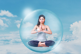 Psychic woman meditating inside a protective bubble floating in the sky