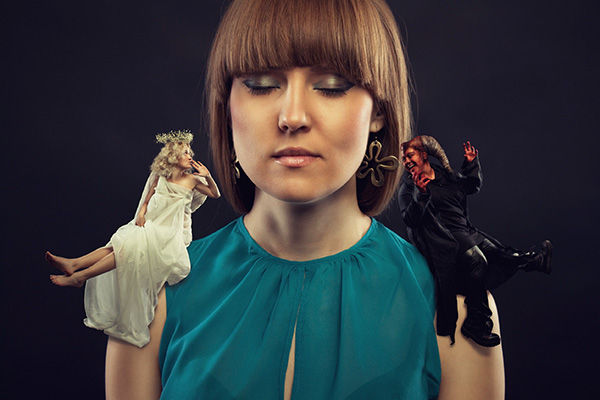 Woman meditating with a demon on one shoulder and an angel on the other